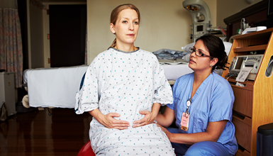 A woman practices breathing exercises with a nurse.