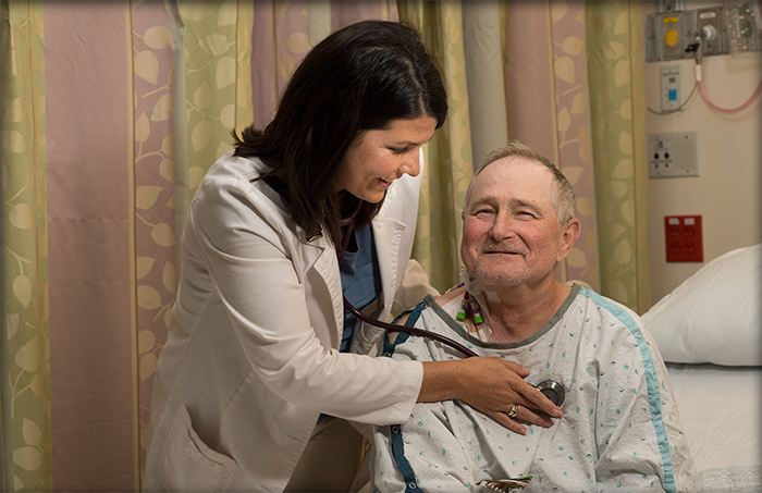 A physician listens to a patient's vitals with a stethoscope