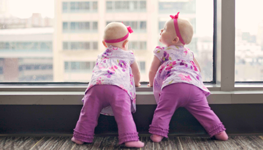 Twin babies look out the window of the hospital. Twin babies look out the window of the hospital.