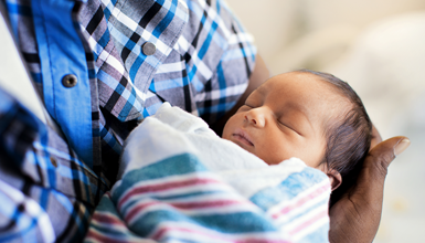 A newborn sleeps in his parents arms