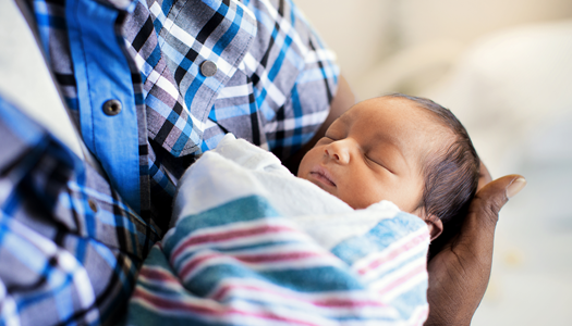 A newborn sleeps in his parents arms