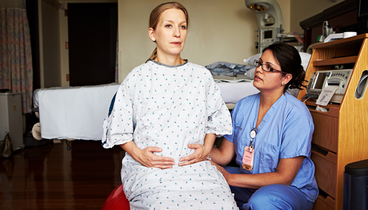 A pregnant woman practices breathing exercises with a physician.