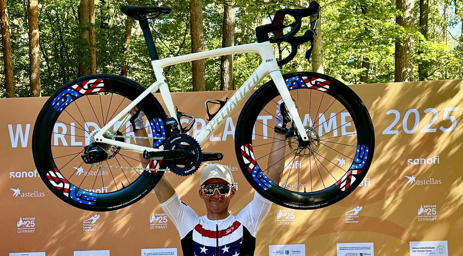 Man holding a race bike up above his shoulders